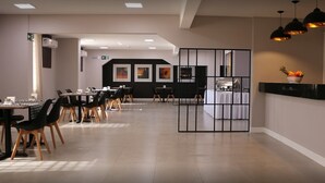 Un comedor moderno con mesas y sillas, una recepción y obras de arte en las paredes.