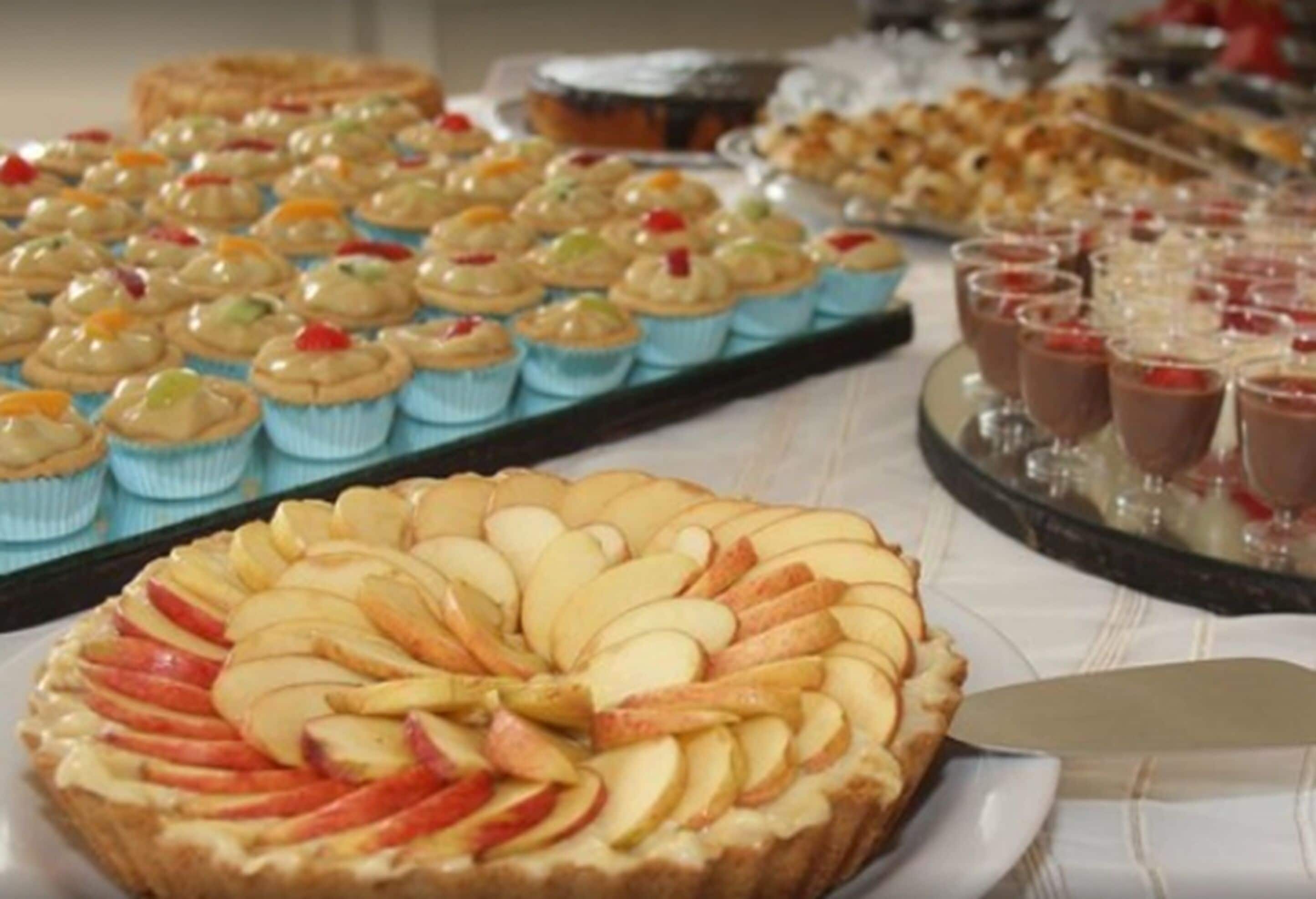 A variety of desserts including a tart with apple slices, cupcakes, and chocolate desserts.