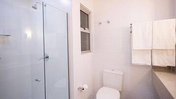 Un baño moderno con ducha envuelta en vidrio, inodoro y lavamanos.