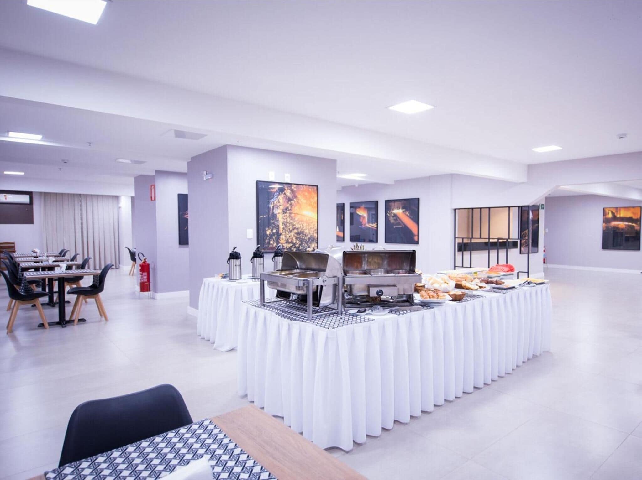 A modern conference room with a buffet setup, white tables, and chairs, and artwork on the walls.