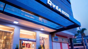 Exterior del Vila Hotel con un diseño moderno, destacando amplias ventanas de vidrio y un cartel llamativo.