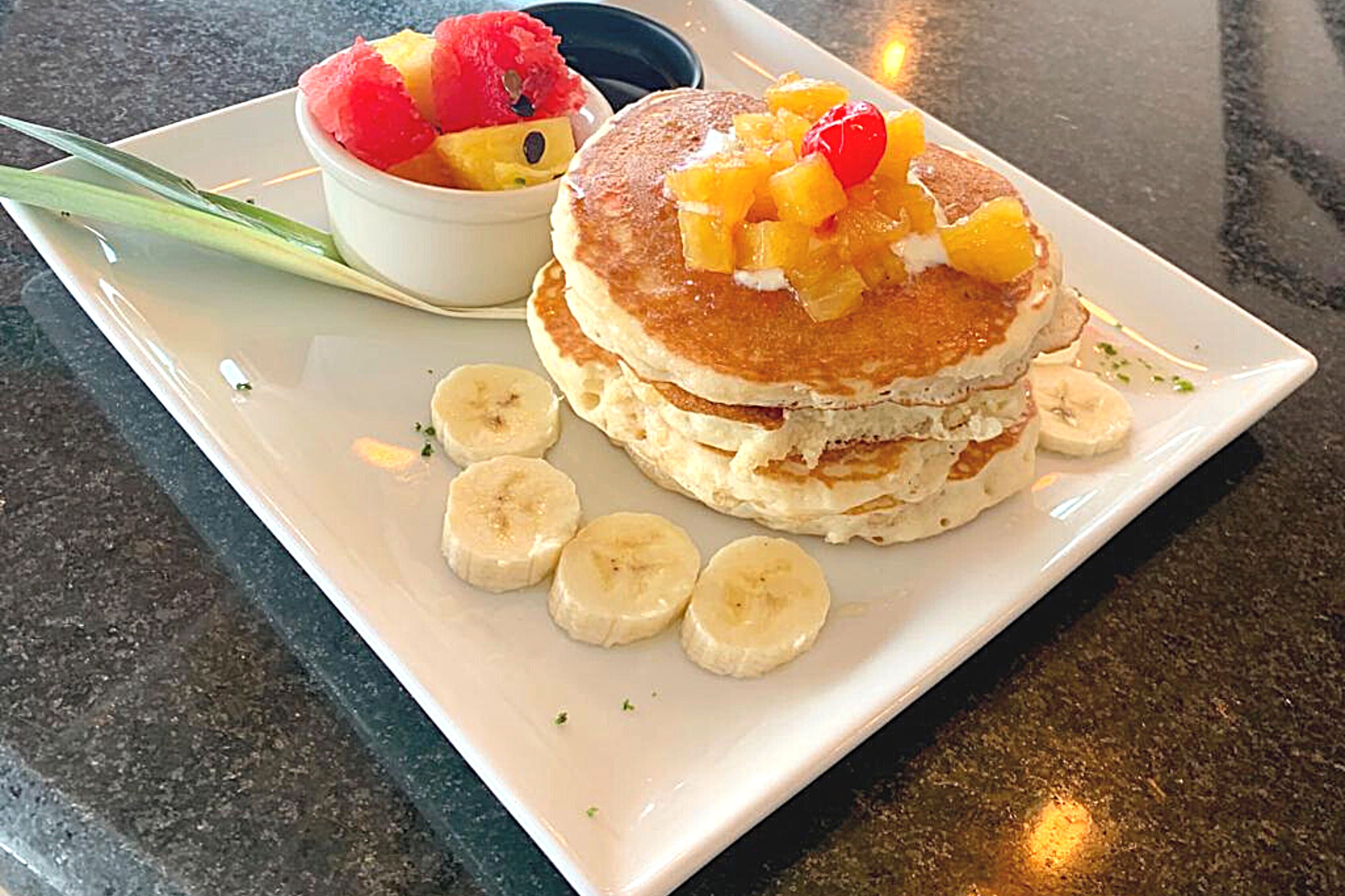 Un plato con tortitas cubiertas de fruta y rodajas de plátano.