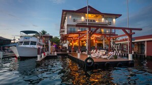 Imóvel à beira-mar com um cais, um barco e um edifício com varanda e área de estar ao ar livre.