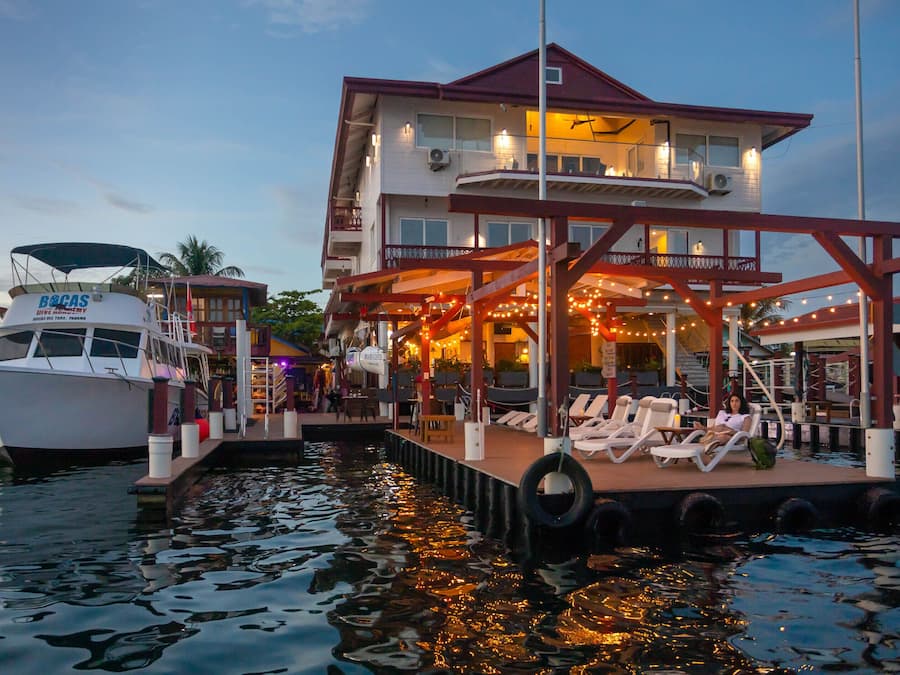 A waterfront property with a dock, a boat, and a building with a balcony and outdoor seating area.