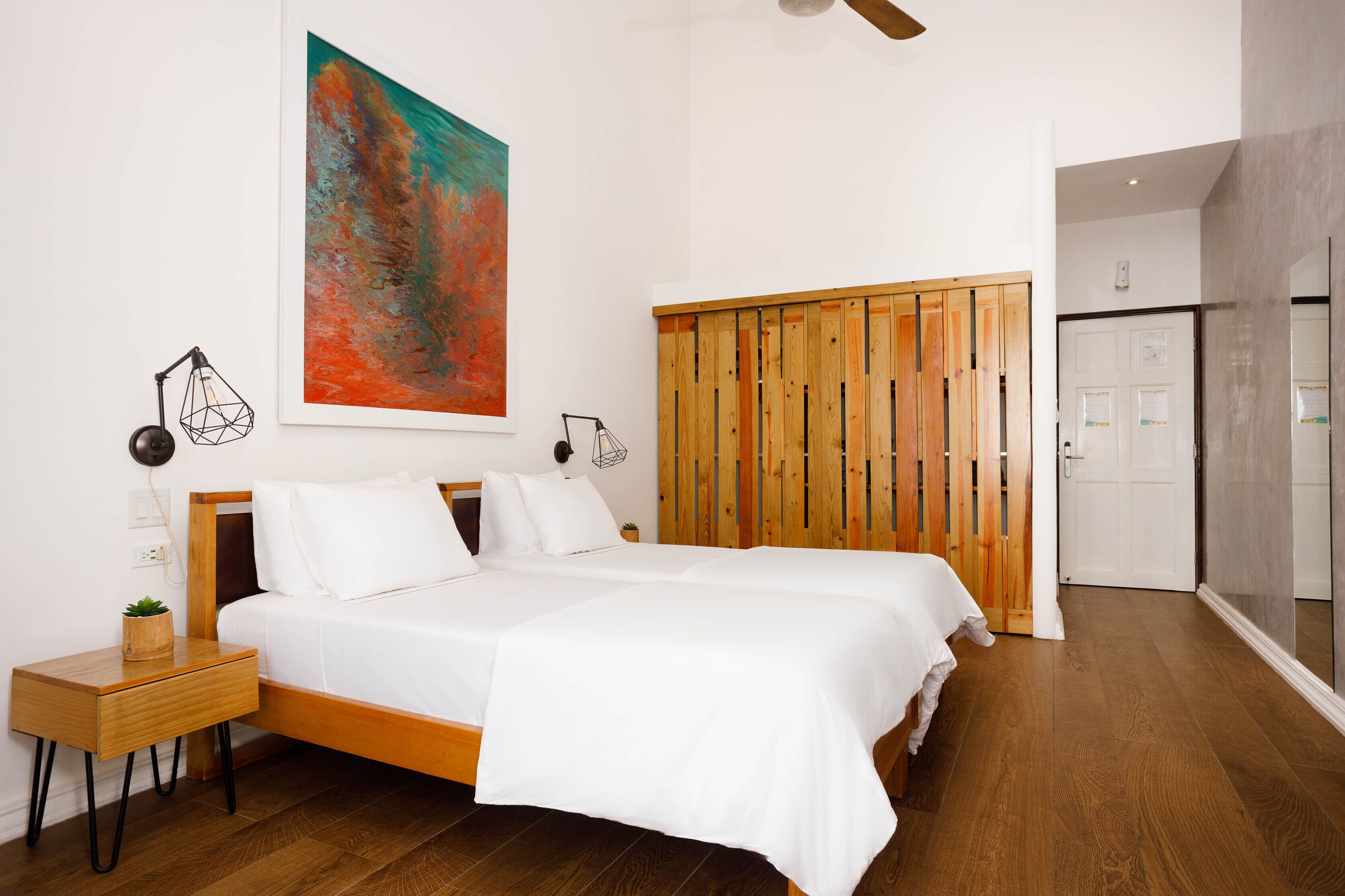 Un dormitorio moderno con una cama grande, un armario de madera y un cuadro en la pared.