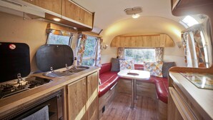 Interior compacto de autocaravana con kitchenette, comedor y zona de estar.