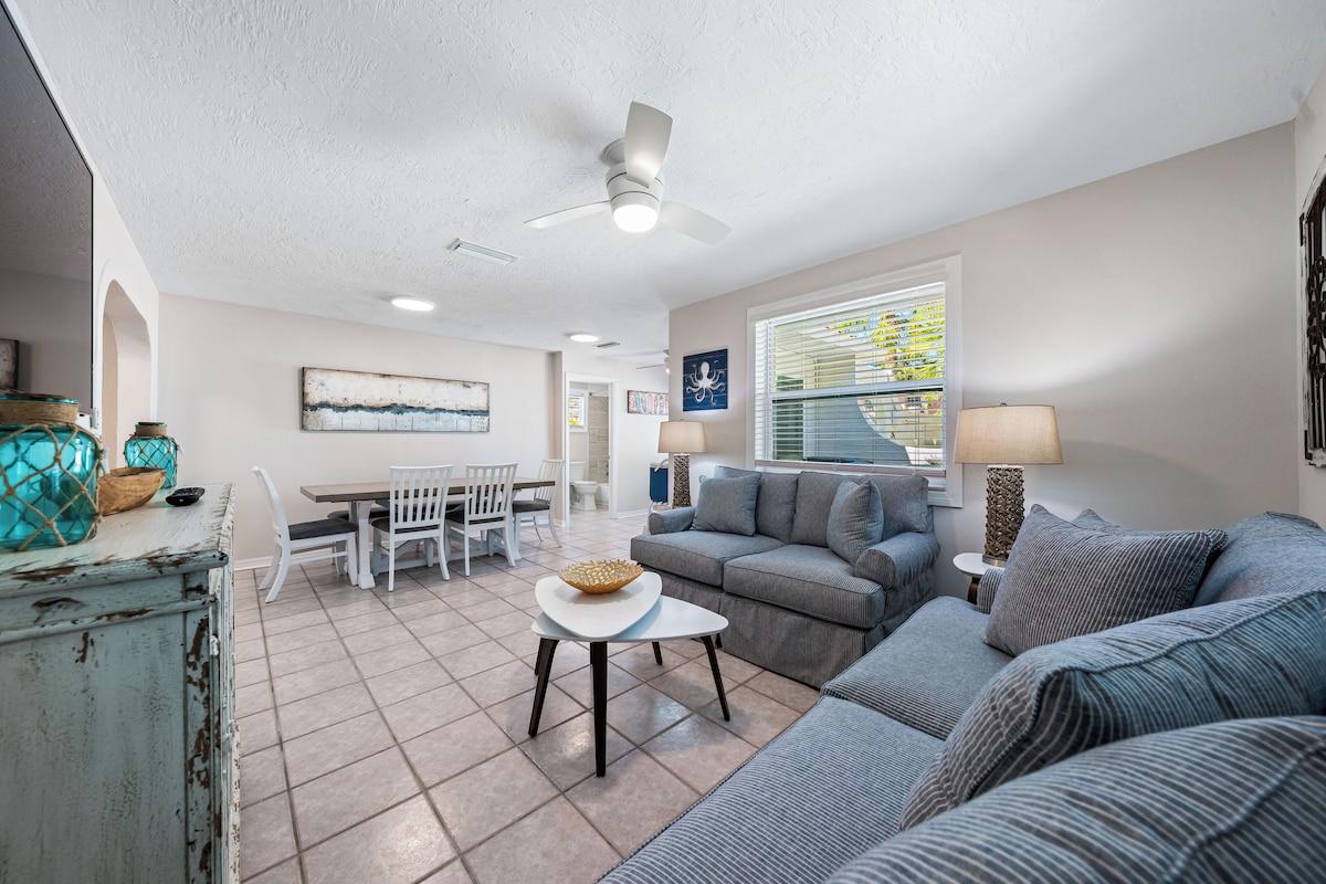 A spacious living room with a gray sofa, a white coffee table, and a ceiling fan.