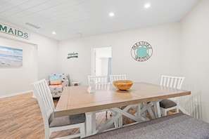 A dining area with a wooden table, white chairs, and a woven bowl. - Bianco Sands by Beachside Management (Siesta Key)