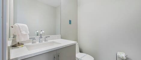 A modern bathroom with a white sink, mirror, and toilet.
