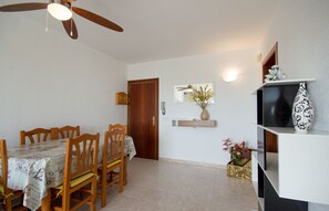 A dining area with a table for four, ceiling fan, and decorative vase.