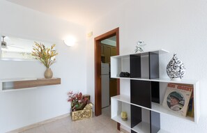 Enter a well-organized space with a large mirror reflecting the area, a shelf unit, and decorative items.