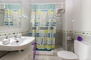 Bathroom features a sink, mirror, toilet, and shower with a curtain.