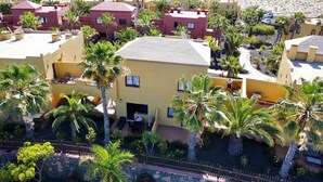 Zona residencial con varios edificios, incluyendo una casa amarilla destacada con balcón y antenas parabólicas.