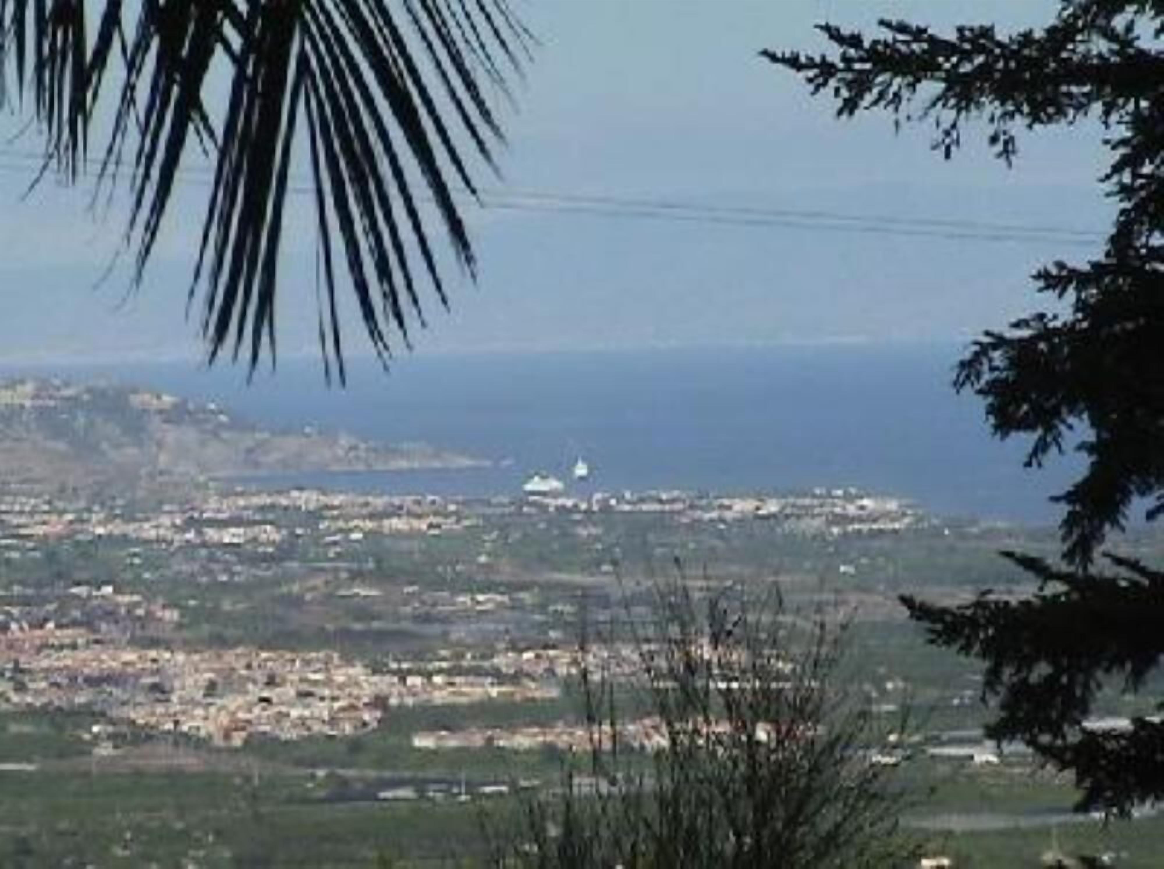 A coastal cityscape with buildings and a lighthouse in the distance.