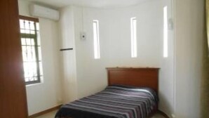 Ein Schlafzimmer mit einem Einzelbett, einem Fenster und einer Tür.