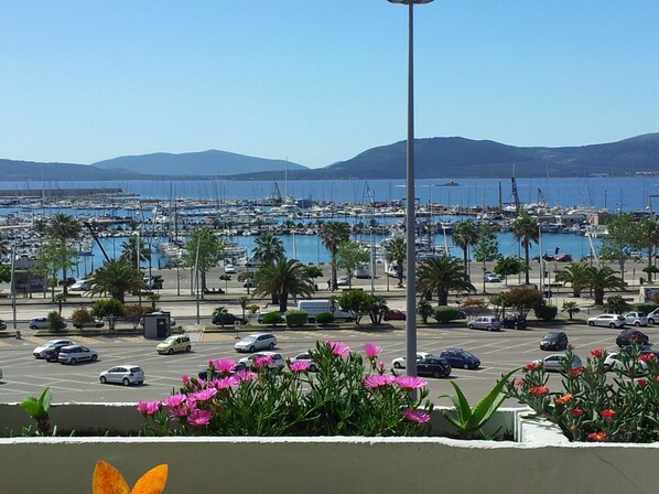 Un port de plaisance avec des bateaux, un parking et un paysage montagneux en arrière-plan.