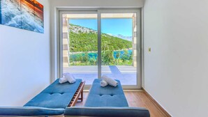 Habitación con dos sillones masajeadors azules, un amplio ventanal corredero que ofrece una vista panorámica de una montaña y un lago.