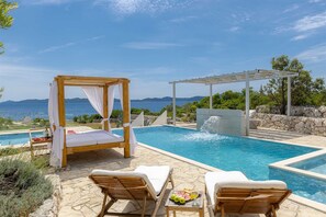 A poolside area with a wooden canopy, lounge chairs, and a table with fruit and drinks. - Villa Oasis, 5 bedrooms, heated Pool, Jacuzzi, BeachFront by MyWaycation (Smokvina)