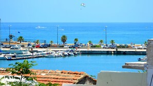 A marina with boats docked, a clear blue sky, and a person flying a kite.