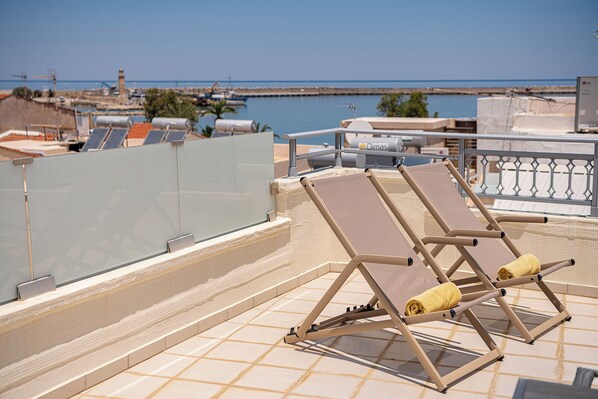 Une terrasse sur le toit, dotée de chaises longues et offrant une vue sur la mer.