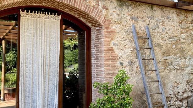 A rustic stone wall with a wooden door and a woven curtain.
