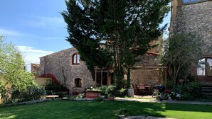 A stone building with a garden patio, a barbecue area, and a swimming pool.