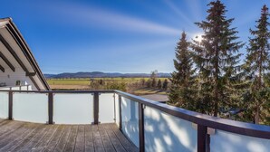 A wooden deck with a glass balustrade overlooking a scenic landscape with mountains and trees. - Fantastic apartment in Goslar am Harz (Goslar-Jerstedt)