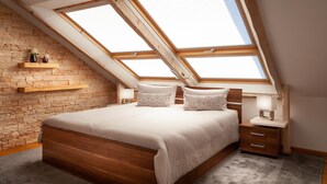 A bedroom with a sloped ceiling, skylights, a wooden bed, a bedside table, and a nightstand. - Fantastic apartment in Goslar am Harz (Goslar-Jerstedt)