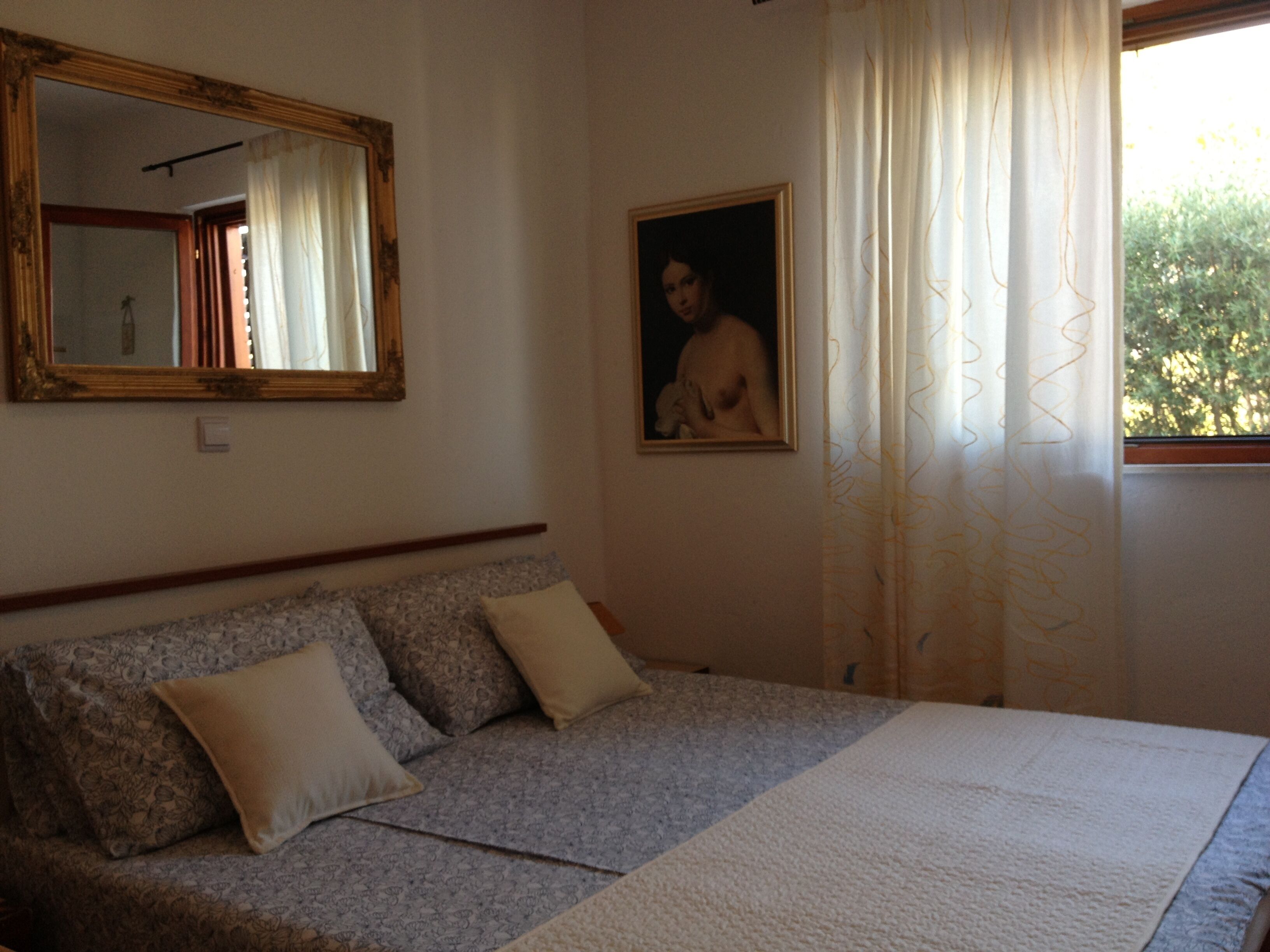 Un dormitorio con cama, sofá, espejo y un cuadro.
