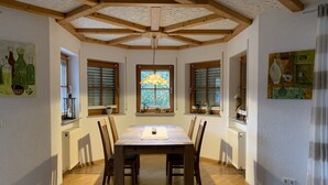 A dining area with a wooden table and chairs, wooden beams on the ceiling, and windows with blinds. - Modern spacious apartment in a quiet south-facing slope. (Kandern)