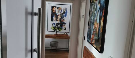 A hallway with a wooden bench, a red carpet, a door, and a wall with a painting.