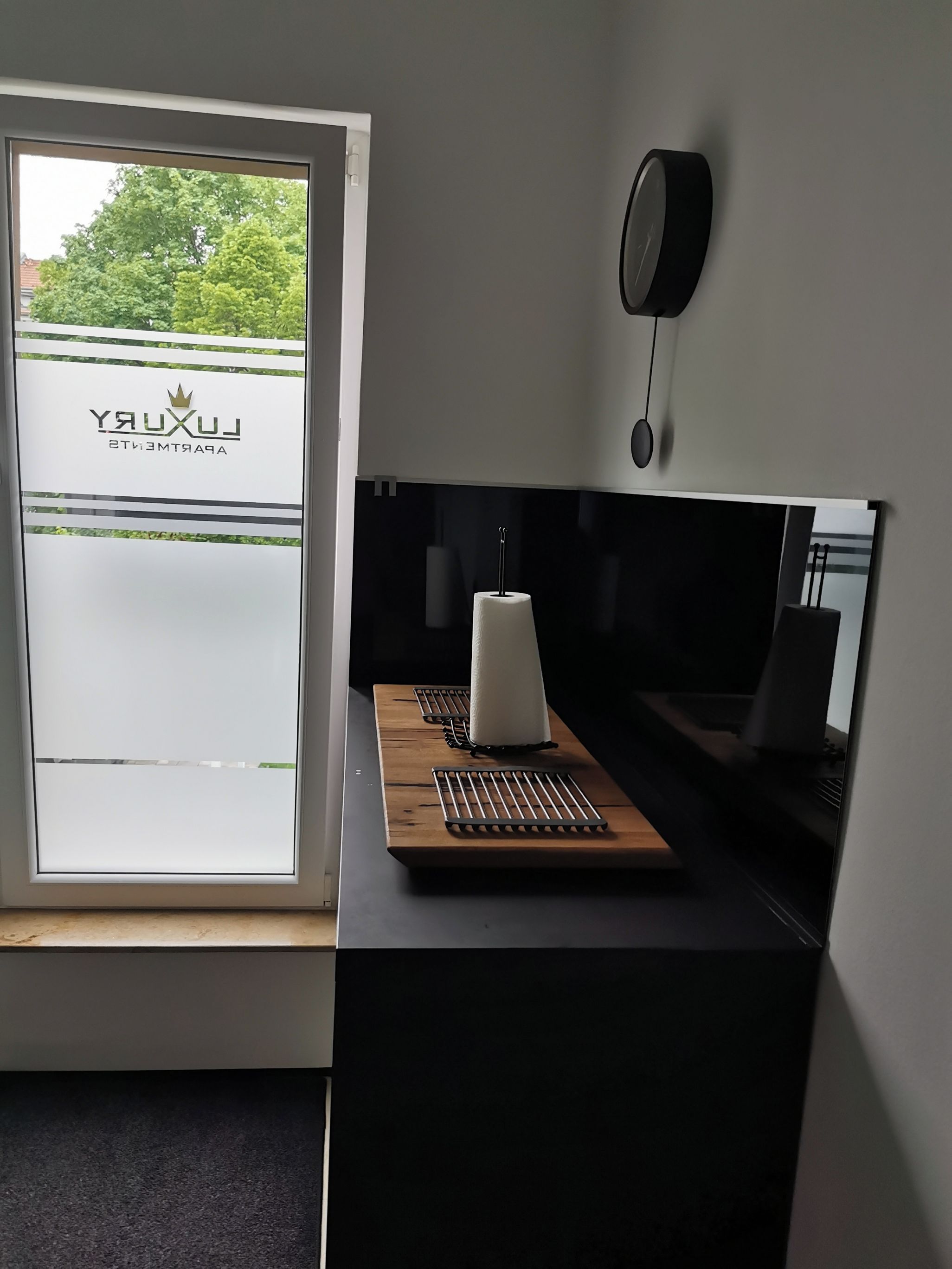 Eine moderne Küche mit Einbauherd, Spüle und einem Fenster mit Blick auf Grünfläche.