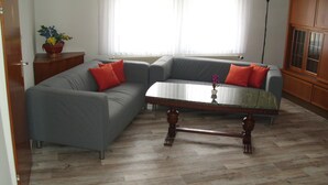 Un salon avec un canapé d’angle gris, une table basse en bois et une plante en pot.