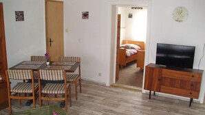 Un espace de vie compact comprenant un coin repas, un téléviseur et une petite chambre.