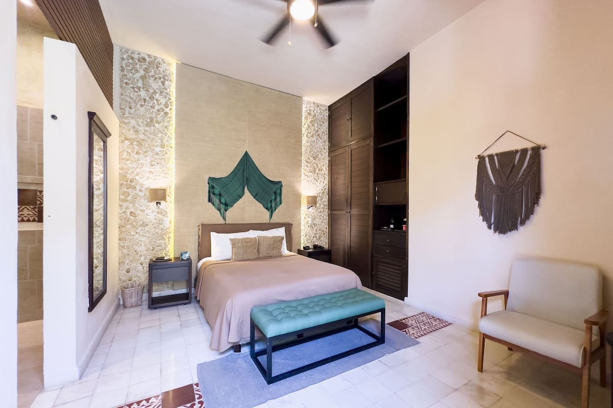 A bedroom with a bed, bedside tables, a bench, a chair, a wardrobe, and a ceiling fan.