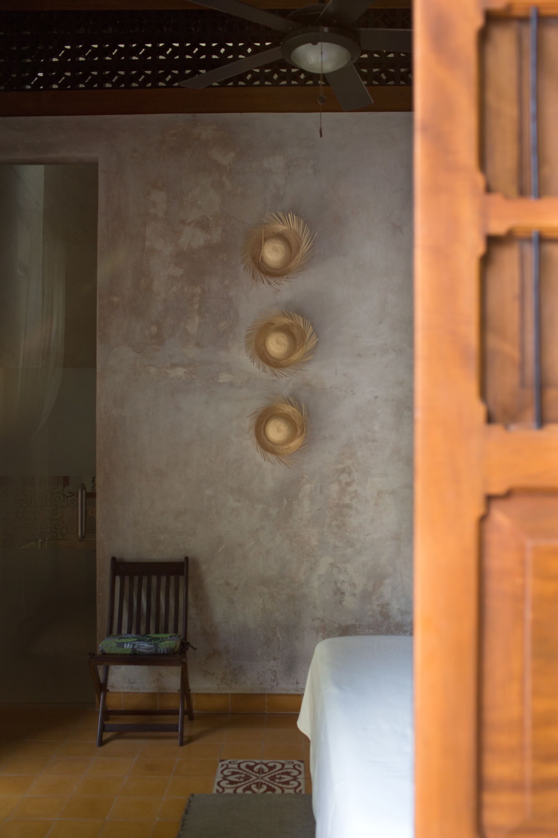 Una habitación con una cama, una silla y un muro con tres adornos.