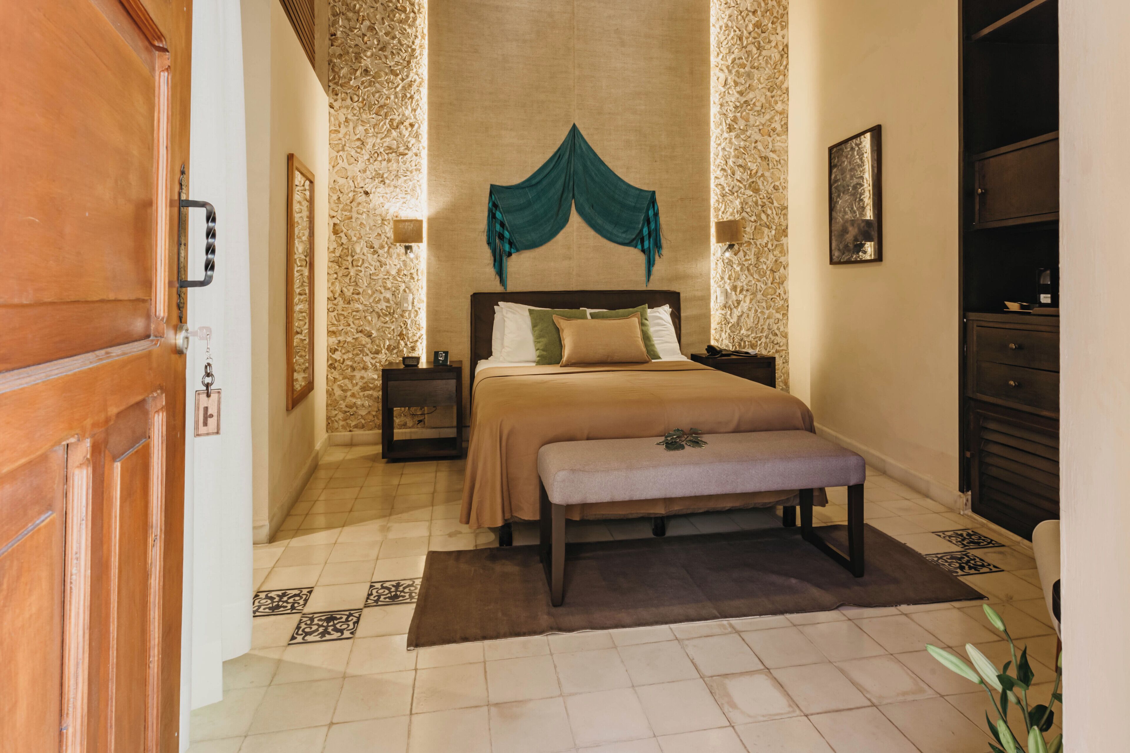 Een slaapkamer met een bed, een bankje, nachtkastjes en een kledingkast.