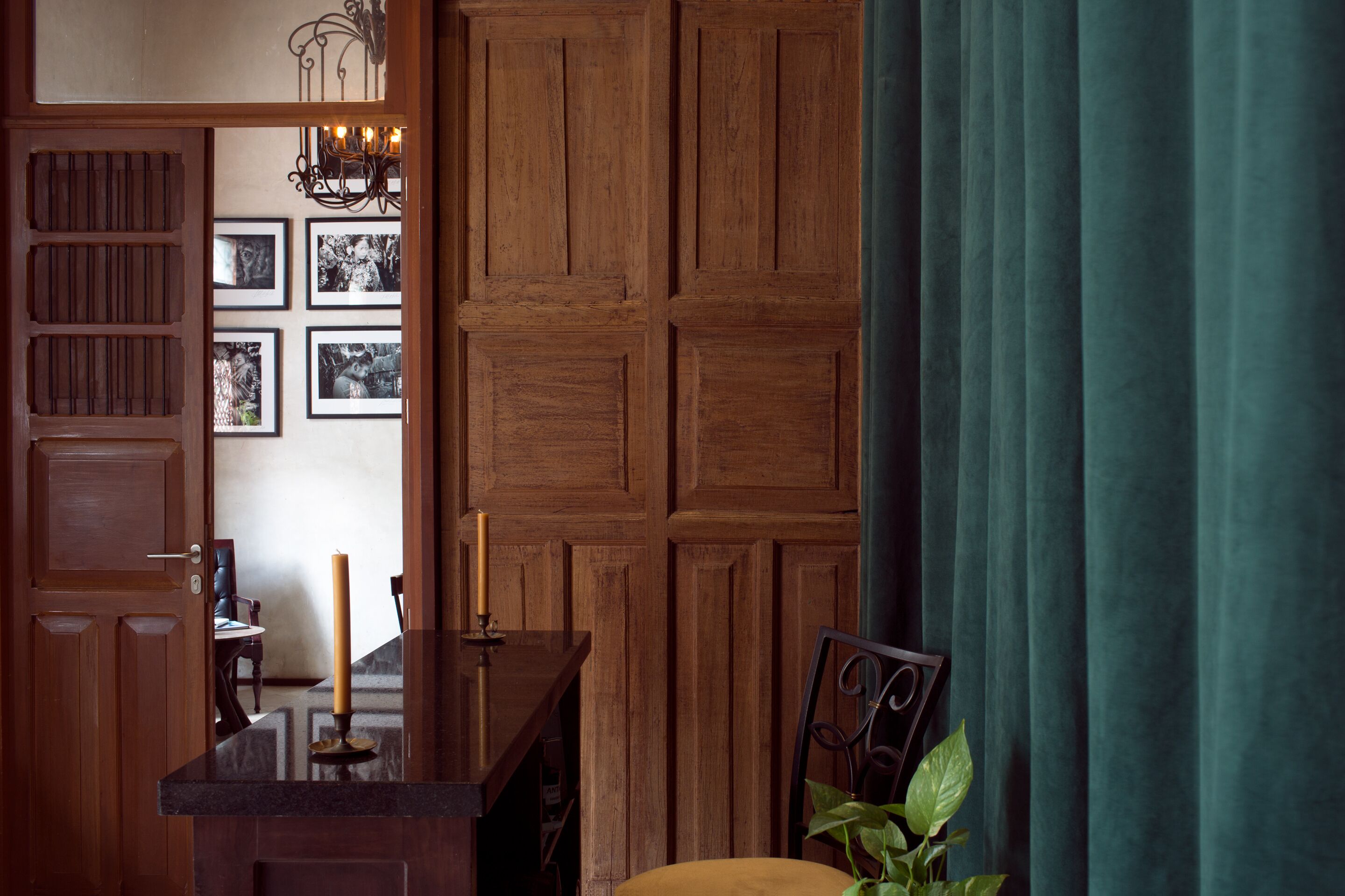 A wooden door with a mirror, a candle, and framed pictures on the wall.