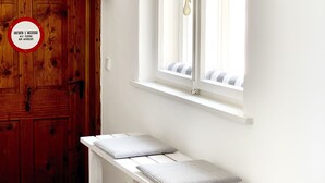 A white bench with striped cushions, a wooden door, and a window with a view of the outside. - 3 Stars Holiday House - Historic ambience of the 18th century. Century (Niederleierndorf)