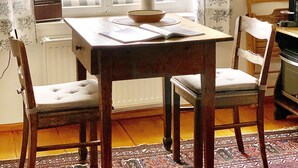 A dining area with a table, chairs, and a view of a green field through a window. - 3 Stars Holiday House - Historic ambience of the 18th century. Century (Niederleierndorf)