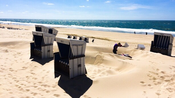 A beach with rows of beach chairs and a person lying on the sand. - Newly renovated, close to the beach, sunny, south-facing balcony, WLAN (Sylt /Westerland)