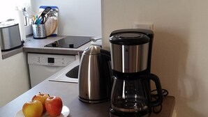 A kitchen with a Bosch dishwasher, a coffee maker, a loaf of bread, and apples on the counter. - Newly renovated, close to the beach, sunny, south-facing balcony, WLAN (Sylt /Westerland)
