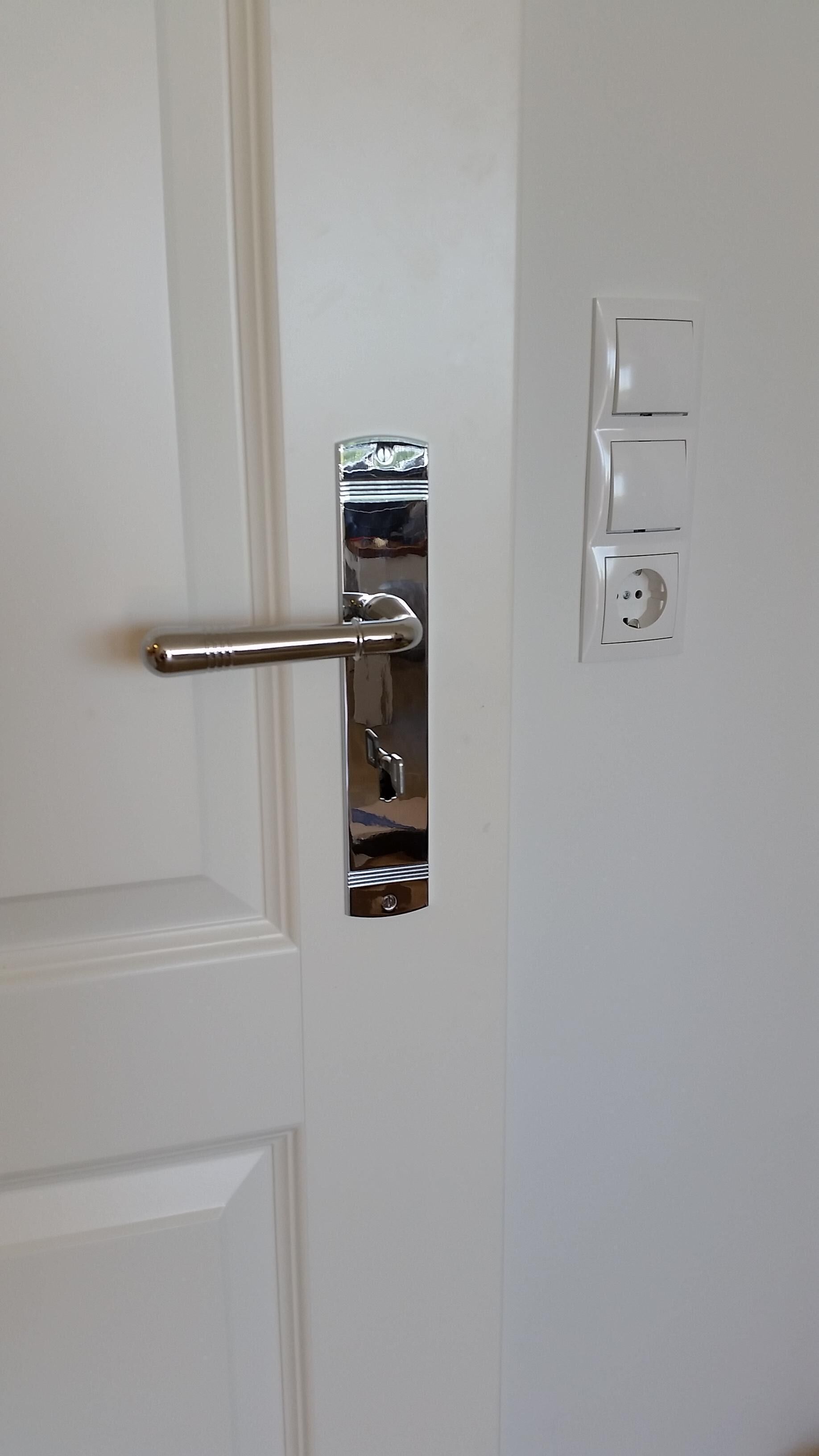 A white door with a metallic handle and a keyhole.