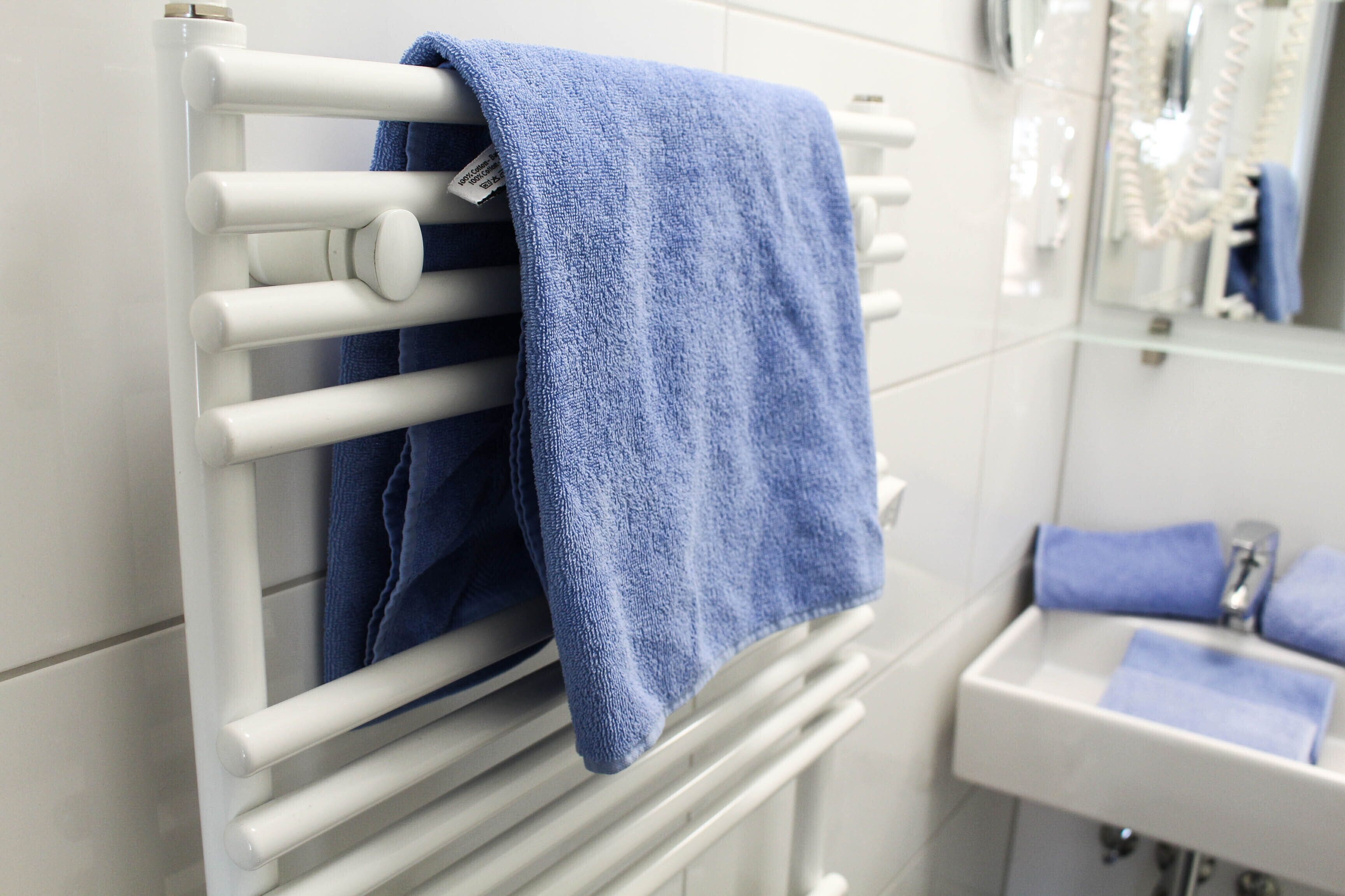 A bathroom with a white radiator, a sink, and a mirror.