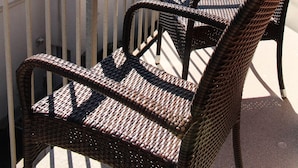 A balcony with wicker furniture and a view of a green landscape. - Newly renovated, close to the beach, sunny, south-facing balcony, WLAN (Sylt /Westerland)