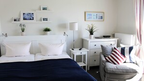 A neatly arranged bedroom with a bed, bedside tables, a dresser, and a chair. - Newly renovated, close to the beach, sunny, south-facing balcony, WLAN (Sylt /Westerland)
