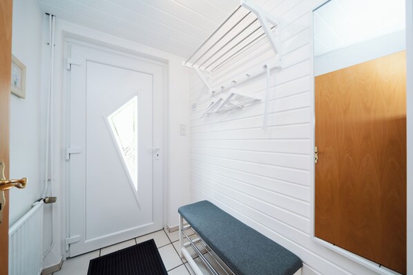 A room with a white door, a bench, a drying rack, and a wooden door. - 4 star premium vacation home Antonia, central, close to the city, (Witzenhausen)