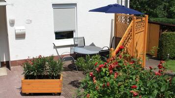 Eine Terrasse mit Tisch und Stühlen, einem Holzzaun und Blumentöpfen.