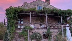 Un bâtiment en pierre doté d’un balcon, recouvert de lierre, et d’une petite fenêtre.