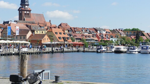 A riverside town with historic buildings, a prominent church tower, and boats docked along the water. - Large apartment (92 sqm) "sea eagle" 1-6 people in a great location (Kargow)